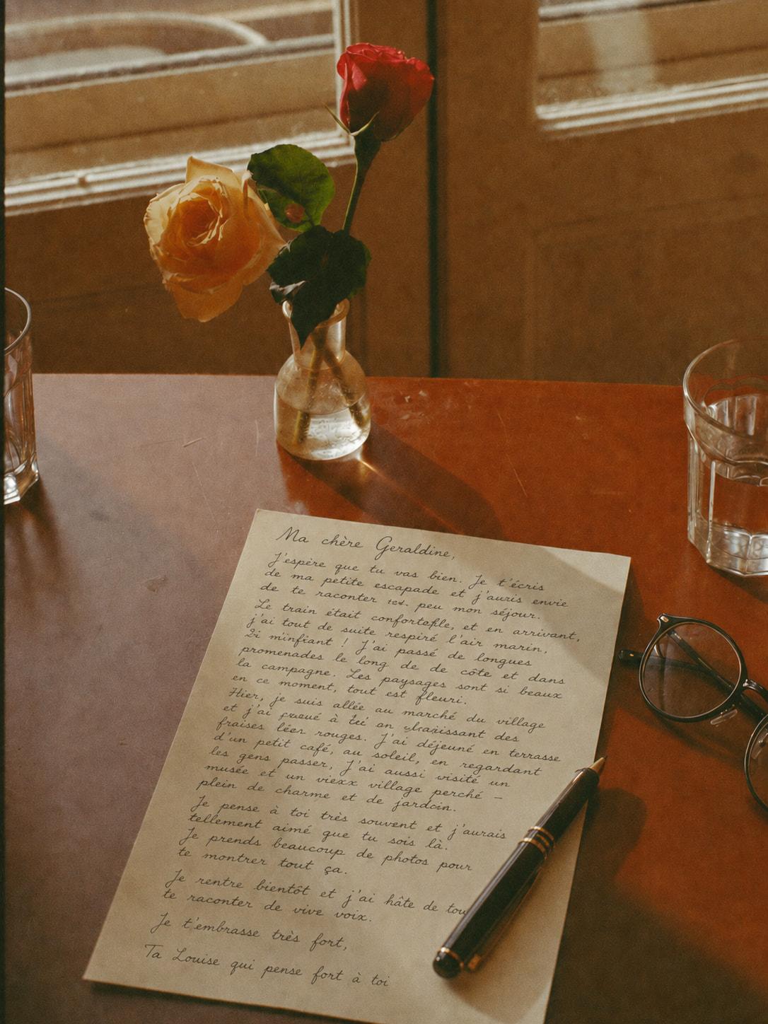 Un bureau d'écriture dans la lumière du matin, une lettre manuscrite, un stylo, des roses de jardin